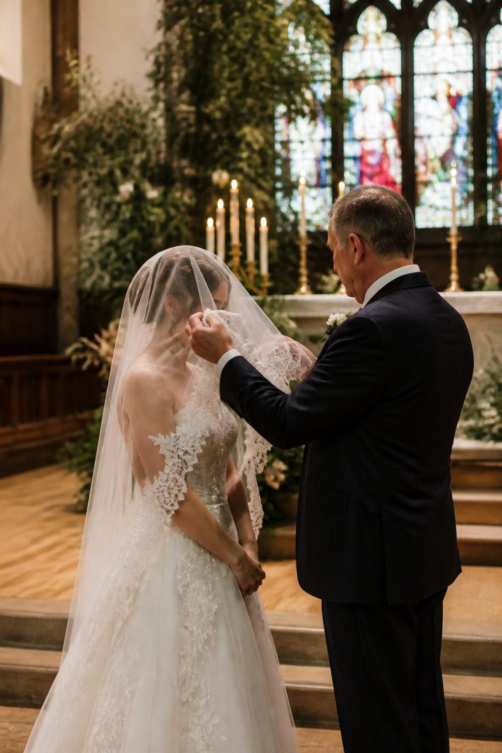 Bride's father lifting her bridal veil at the altar.