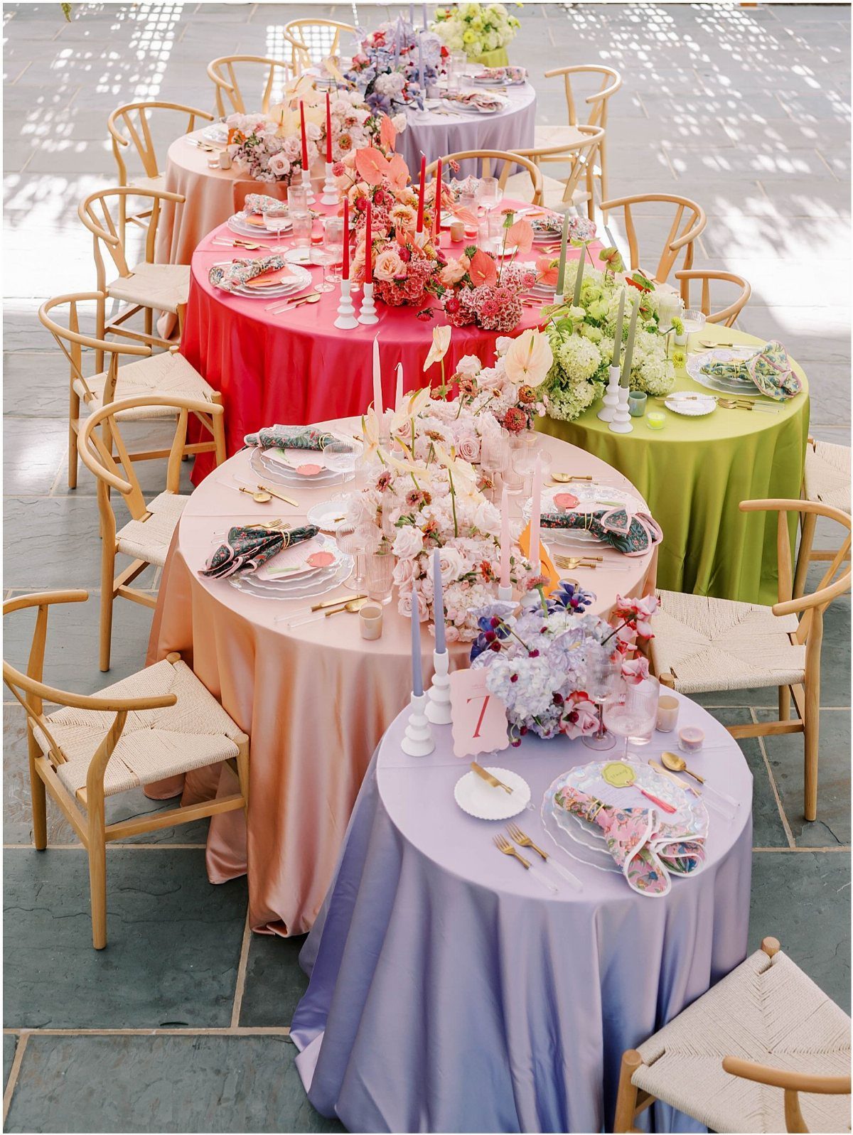 21 Colorful Wedding Table Settings for Every Style and Budget 15 Round tables with vibrant pink, green, peach, and lavender tablecloths and floral centerpieces outdoors.
