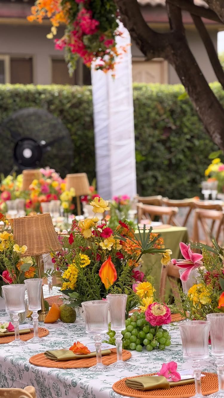 21 Colorful Wedding Table Settings for Every Style and Budget 1 Vibrant floral centerpieces in yellow and orange hues arranged on a decorated outdoor wedding table.