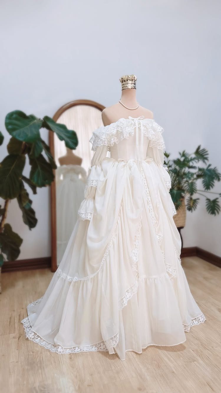 A cream white vintage wedding dress with lace trim displayed on a mannequin.