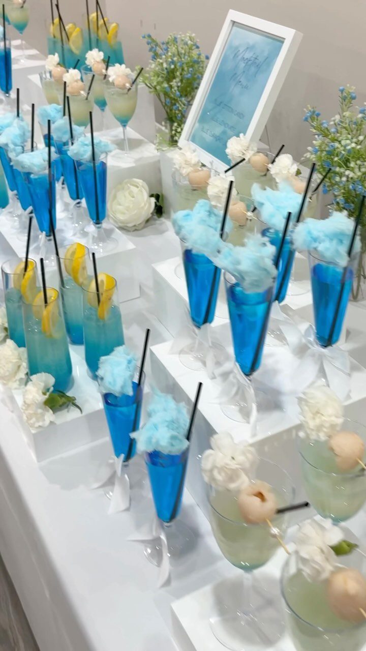 13 Cute and Fun Wedding Ideas for Guests Your Guests Will Love 11 Blue and yellow cocktails garnished with cotton candy and flowers arranged on white tiered stands.