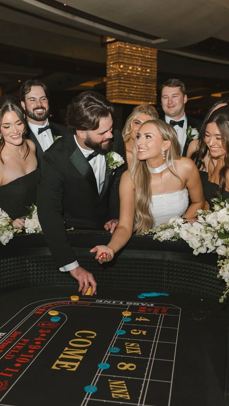 A wedding party gathers around a roulette table as a man places a betting chip.