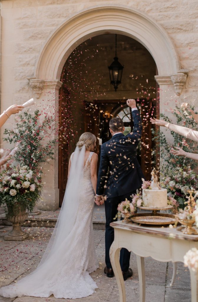 Couple celebrating a ceremony with dried petals and stone walls.