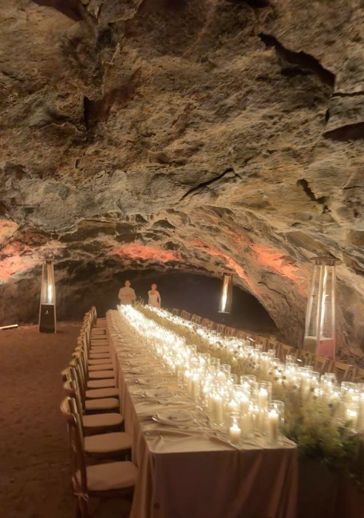 10 Ethereal and Romantic Wedding Ideas That Feel Like a Dream 10 A long dining table covered in glowing candles inside a large, illuminated rocky cave.