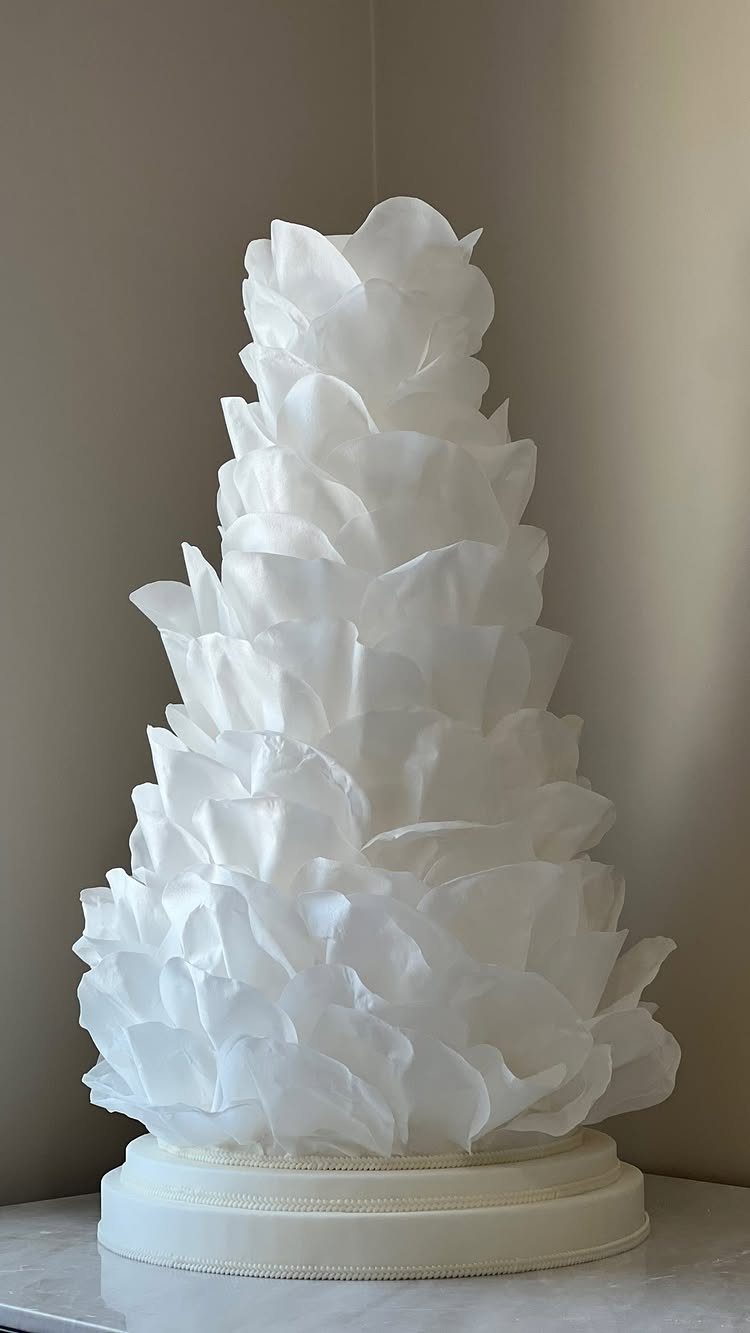 10 Ethereal and Romantic Wedding Ideas That Feel Like a Dream 4 A white wedding cake featuring delicate, translucent ruffles resembling soft flower petals.