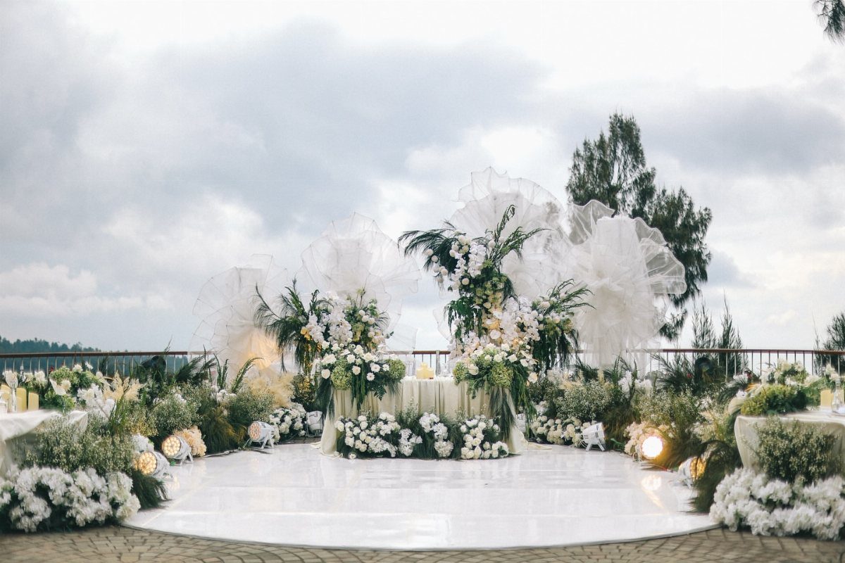 10 Ethereal and Romantic Wedding Ideas That Feel Like a Dream 5 White wedding decor with lush greenery and large translucent ruffles on a white dance floor.