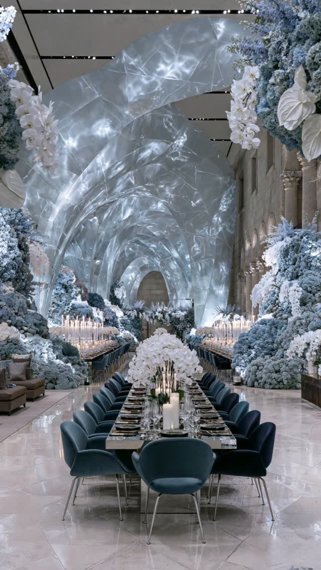 10 Ethereal and Romantic Wedding Ideas That Feel Like a Dream 9 A luxurious wedding reception hall with blue velvet chairs and a glowing, ethereal sculptural ceiling installation.