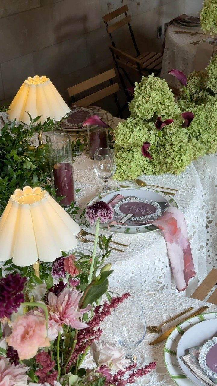 Floral wedding table setting with pink flowers, green hydrangeas, and small glowing table lamps.