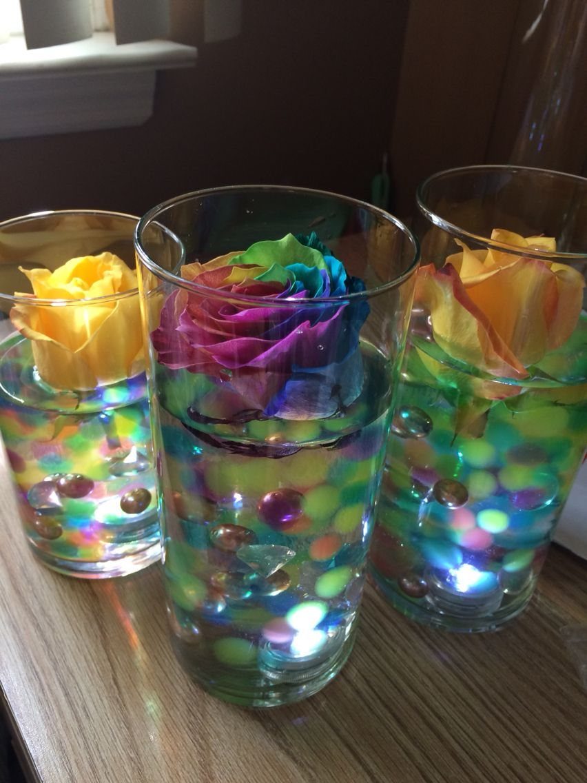 Three glass vases filled with colorful water beads, pearls, and floating roses illuminated from below.
