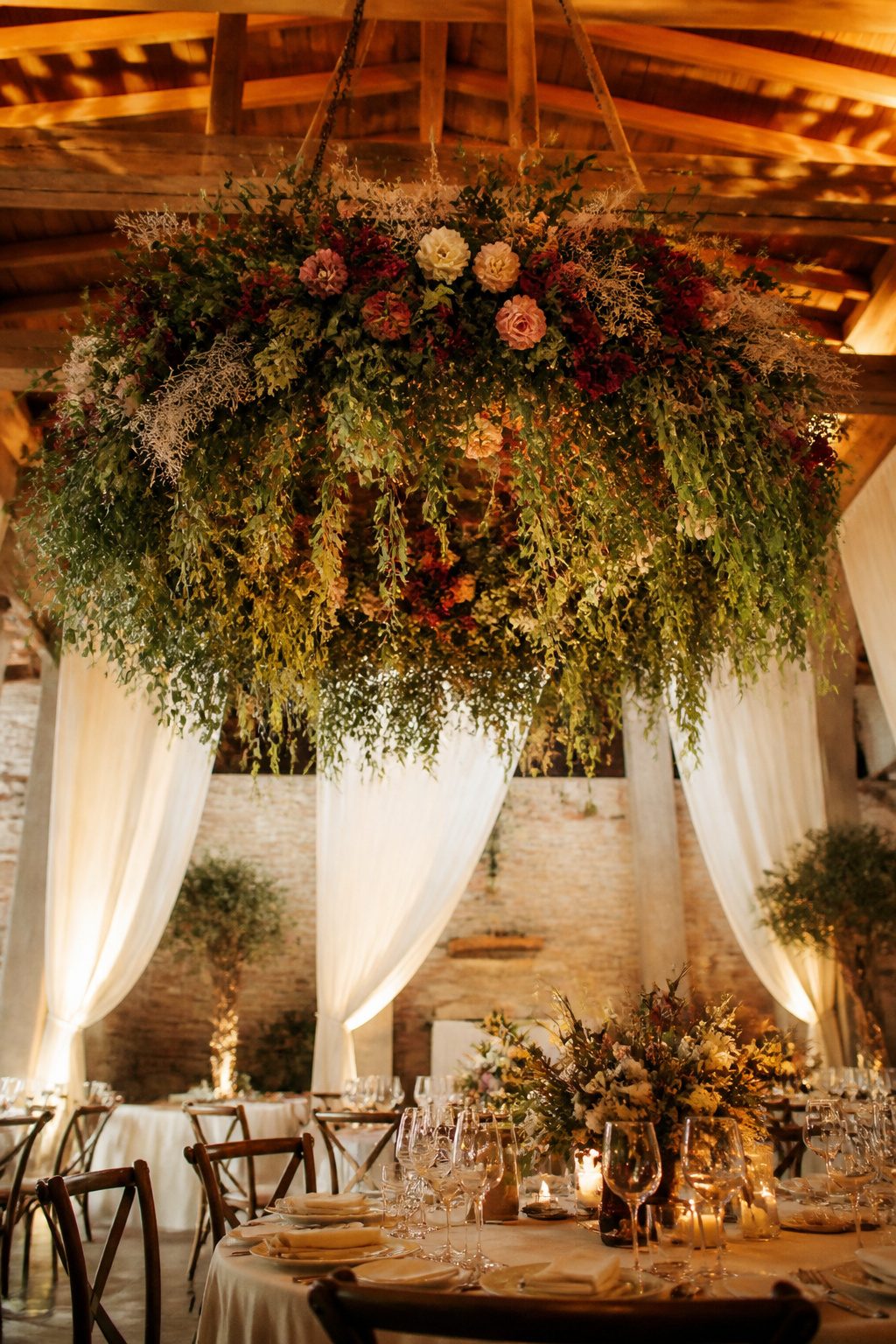 Floral chandeliers hanging from the ceiling at a wedding.