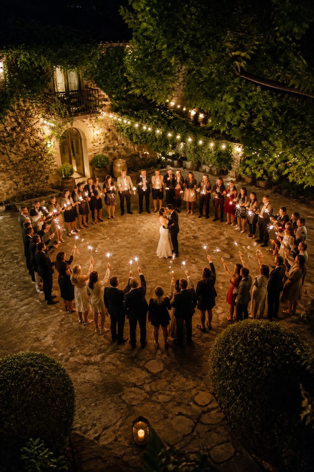 Guests holding sparklers in a circle at a wedding.