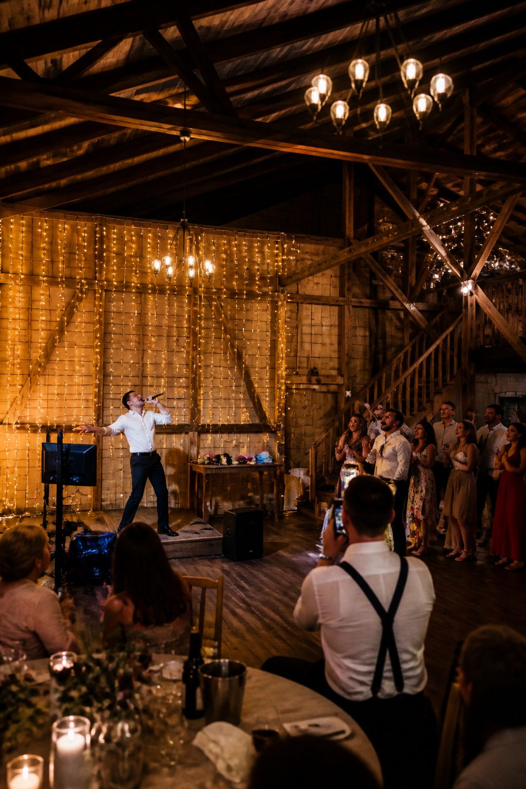 Guests singing karaoke at a lively wedding reception.