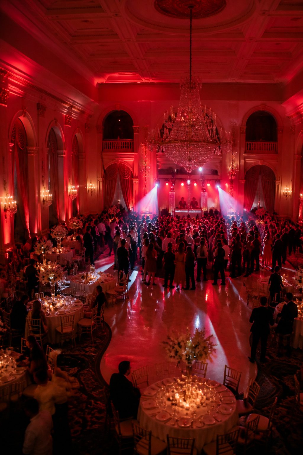 Guests dancing under red lighting at a wedding reception.