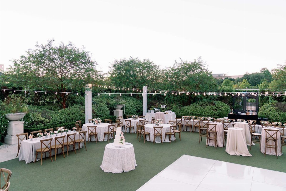 Garden Estate Wedding: 12 Ideas for Ceremony and Reception 4 Wedding reception tables with white linens and wooden chairs set on a green lawn outdoors.