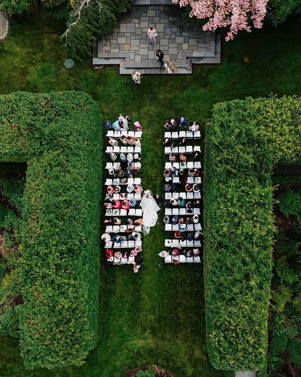 Garden Estate Wedding: 12 Ideas for Ceremony and Reception 3 Aerial view of a wedding ceremony with guests seated in a green garden surrounded by tall hedges.
