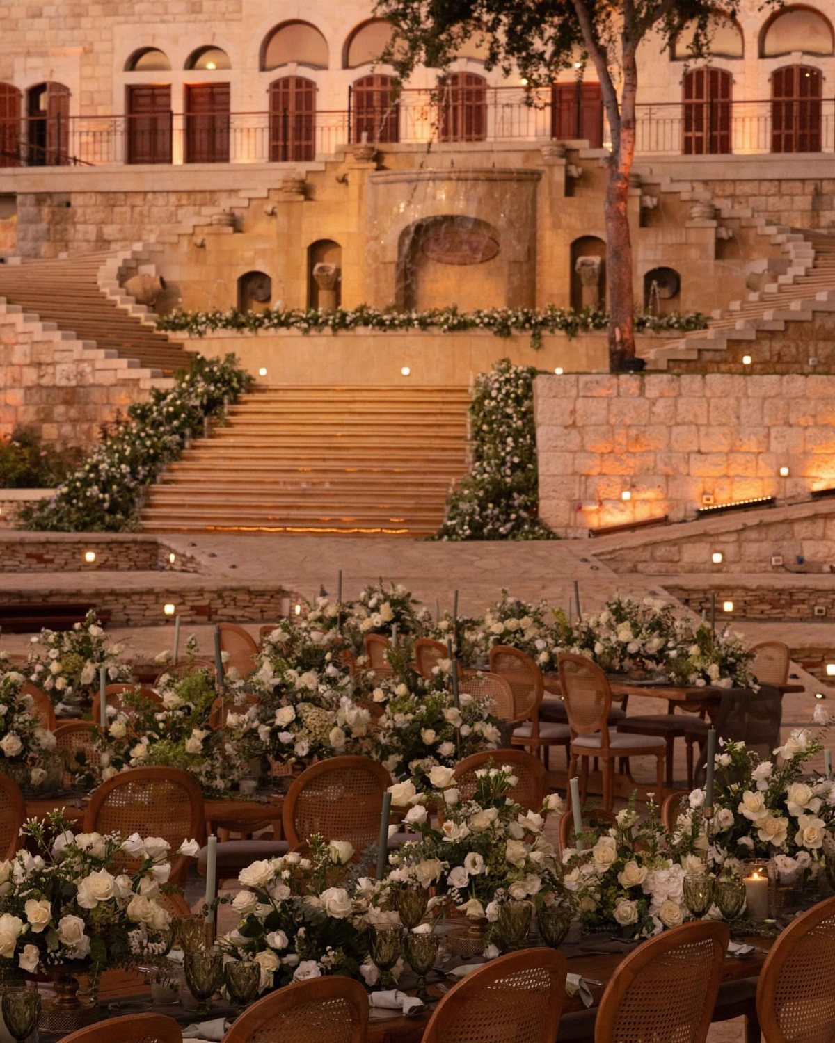 Garden Estate Wedding: 12 Ideas for Ceremony and Reception 6 Wedding reception tables with white flowers set against tiered stone terraces and stairs at night.