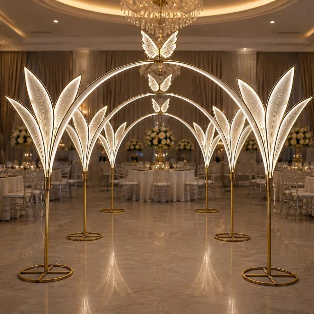 23 Indoor Wedding Decorations for Ceremony and Reception 17 Illuminated golden leaf-shaped arches forming a pathway through a decorated wedding reception ballroom.