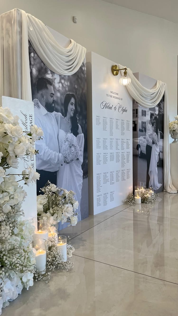 23 Indoor Wedding Decorations for Ceremony and Reception 13 Large wedding seating chart sign flanked by black and white couple portraits and white flowers.