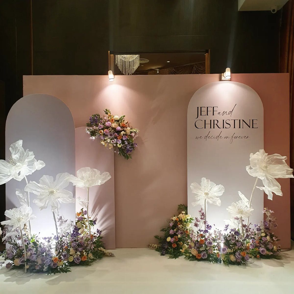 23 Indoor Wedding Decorations for Ceremony and Reception 5 A dusty rose arched photo backdrop decorated with colorful flowers and large white fabric blooms.