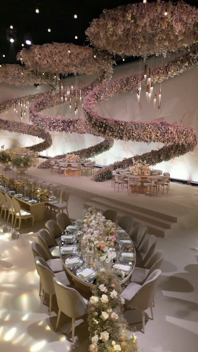 23 Indoor Wedding Decorations for Ceremony and Reception 14 Floral wave installations cascade down walls above elegantly set wedding reception tables in a large hall.
