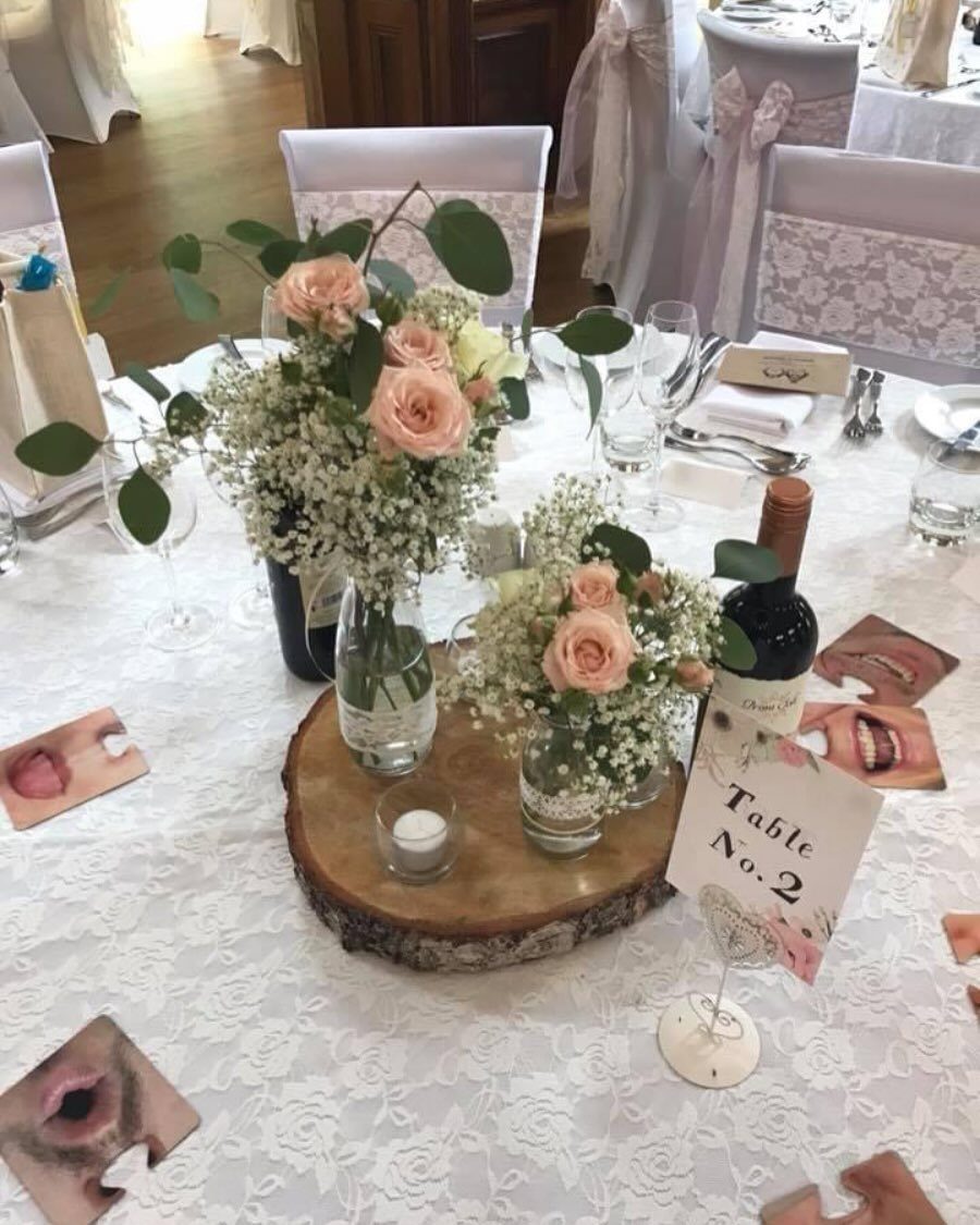 10 Lace and Greenery Wedding Table Ideas to Try 6 Pink roses and greenery in glass vases on a wood slice centerpiece with a small candle.
