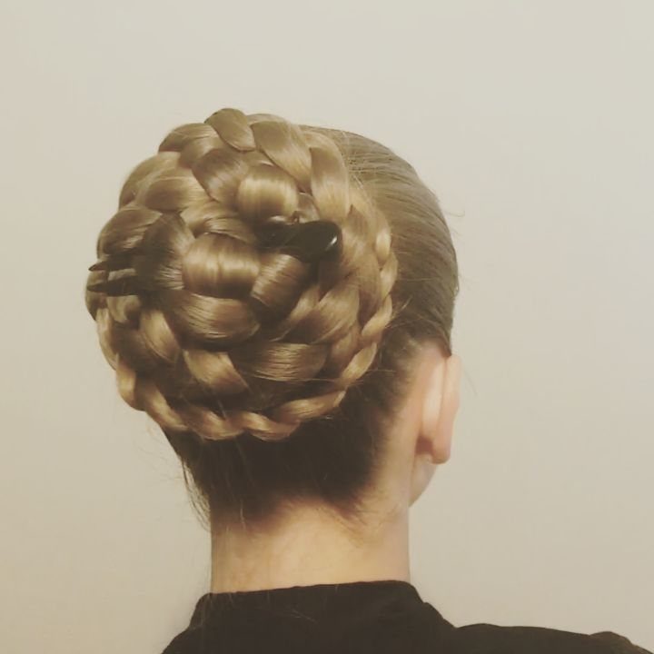 A person with blonde hair styled in a large, intricate braided updo secured with clips.