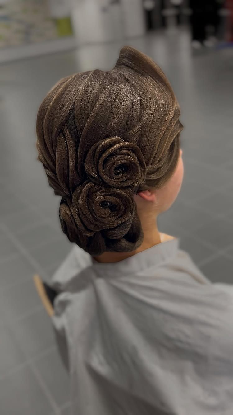 Intricate brown hair styled into large rose-shaped curls at the nape of the neck.