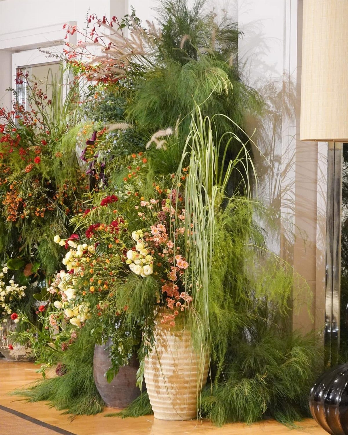 Lush wildflower arrangements with tall grasses and greenery in large ceramic vases.