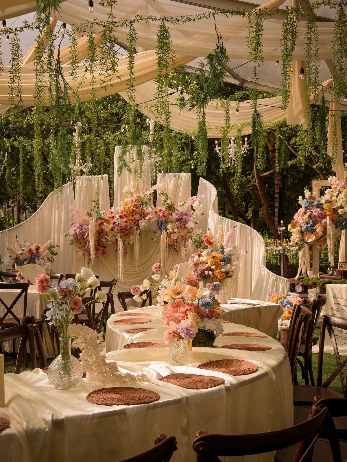 Simple Garden Wedding Reception Outdoor: 14 Stylish Ideas to Copy 12 Wedding reception tables with floral centerpieces and wooden chairs under a draped garden canopy.