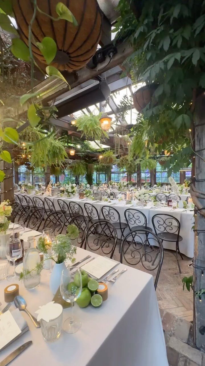 Simple Garden Wedding Reception Outdoor: 14 Stylish Ideas to Copy 1 Long wedding reception table set with white linens inside a lush, plant-filled glass greenhouse.