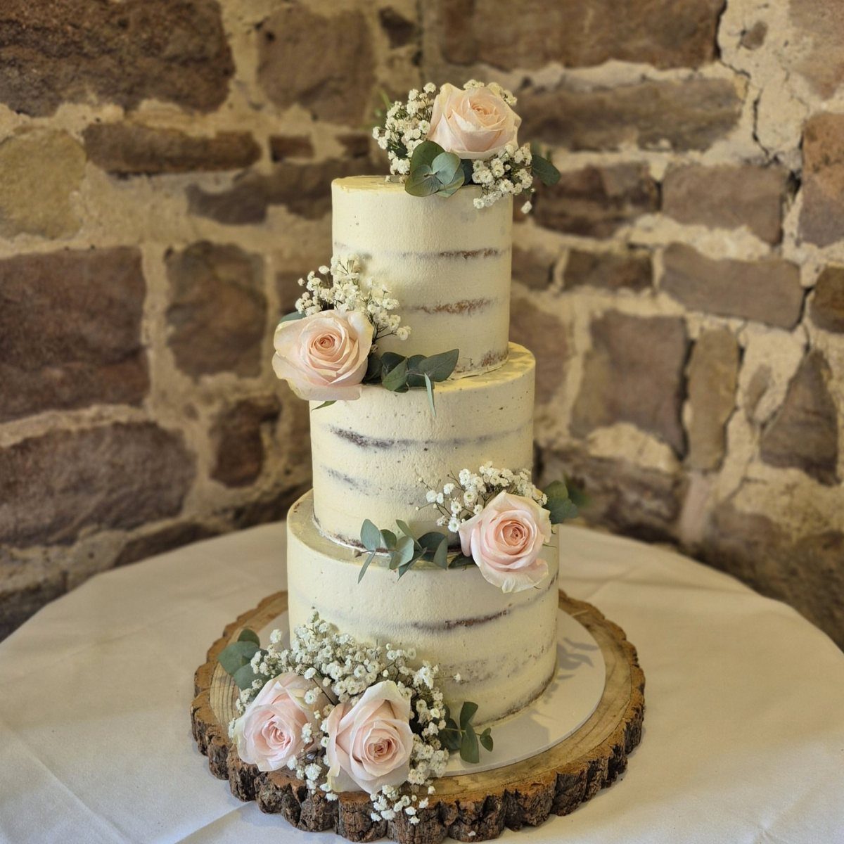 Simple Garden Wedding Reception Outdoor: 14 Stylish Ideas to Copy 8 A three-tier naked cake decorated with pink roses and baby's breath on a wooden base.