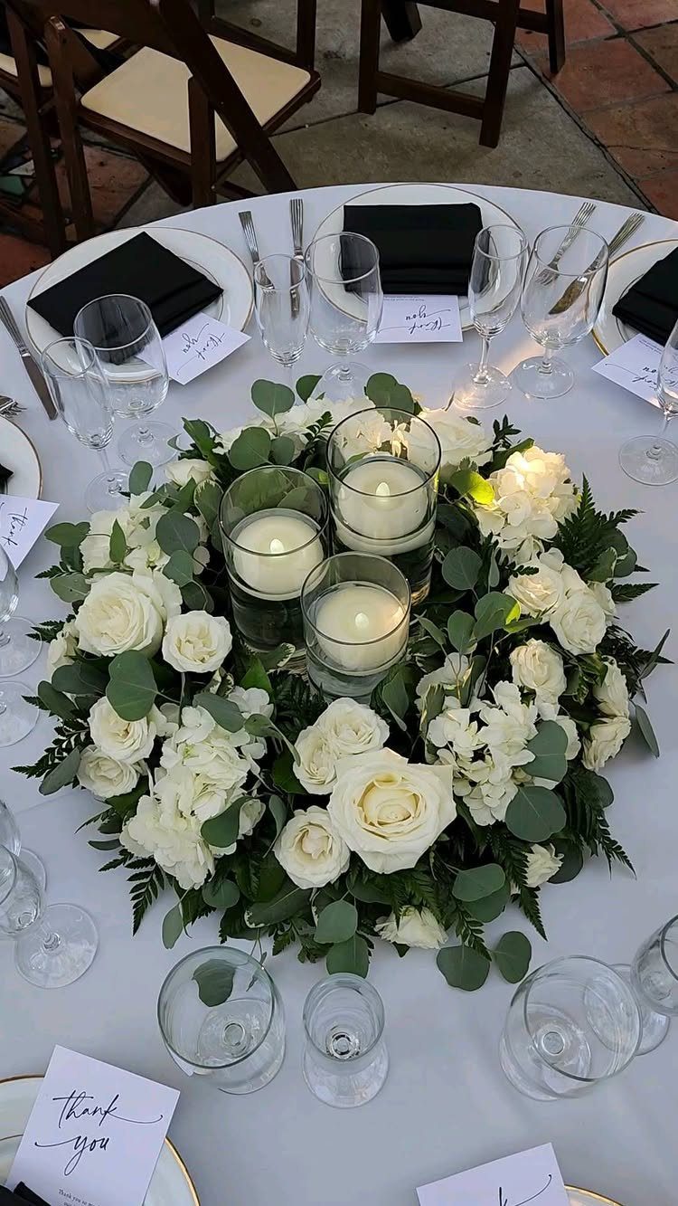 8 Simple Wedding Centerpieces for Budget-Friendly Tables 2 White rose and hydrangea centerpiece with floating candles in glass cylinders on a wedding table.