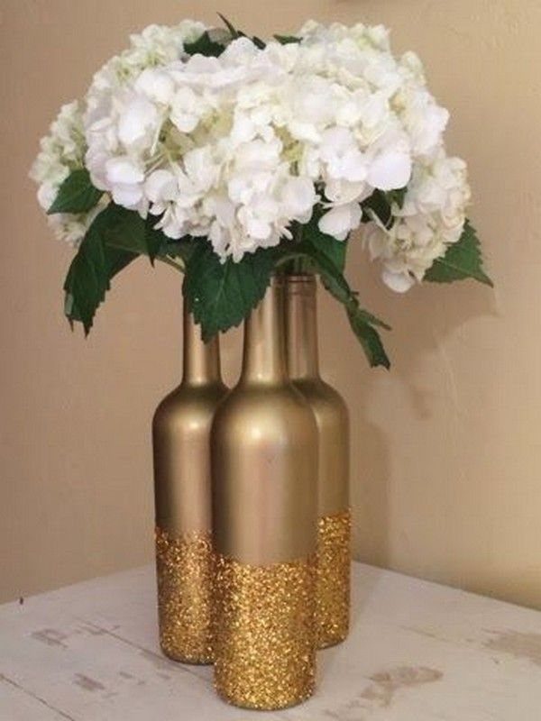 8 Simple Wedding Centerpieces for Budget-Friendly Tables 7 Gold metallic bottles with glitter bottoms holding a large bouquet of white hydrangeas.