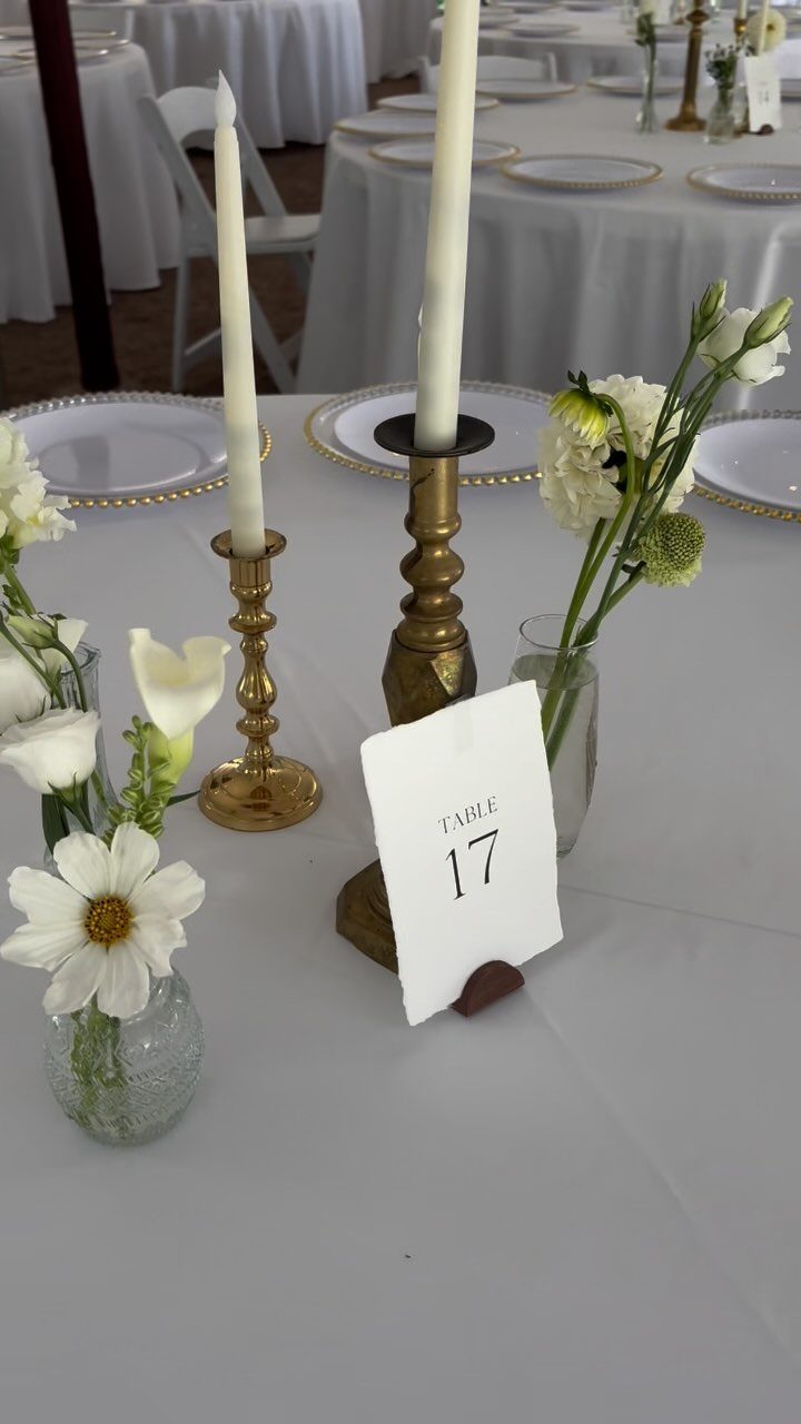 8 Simple Wedding Centerpieces for Budget-Friendly Tables 4 Small glass bud vases with white flowers and tall taper candles on a wedding table.