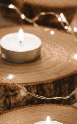8 Simple Wedding Centerpieces for Budget-Friendly Tables 3 Wood slice bases topped with tea light candles and surrounded by twinkling fairy lights.