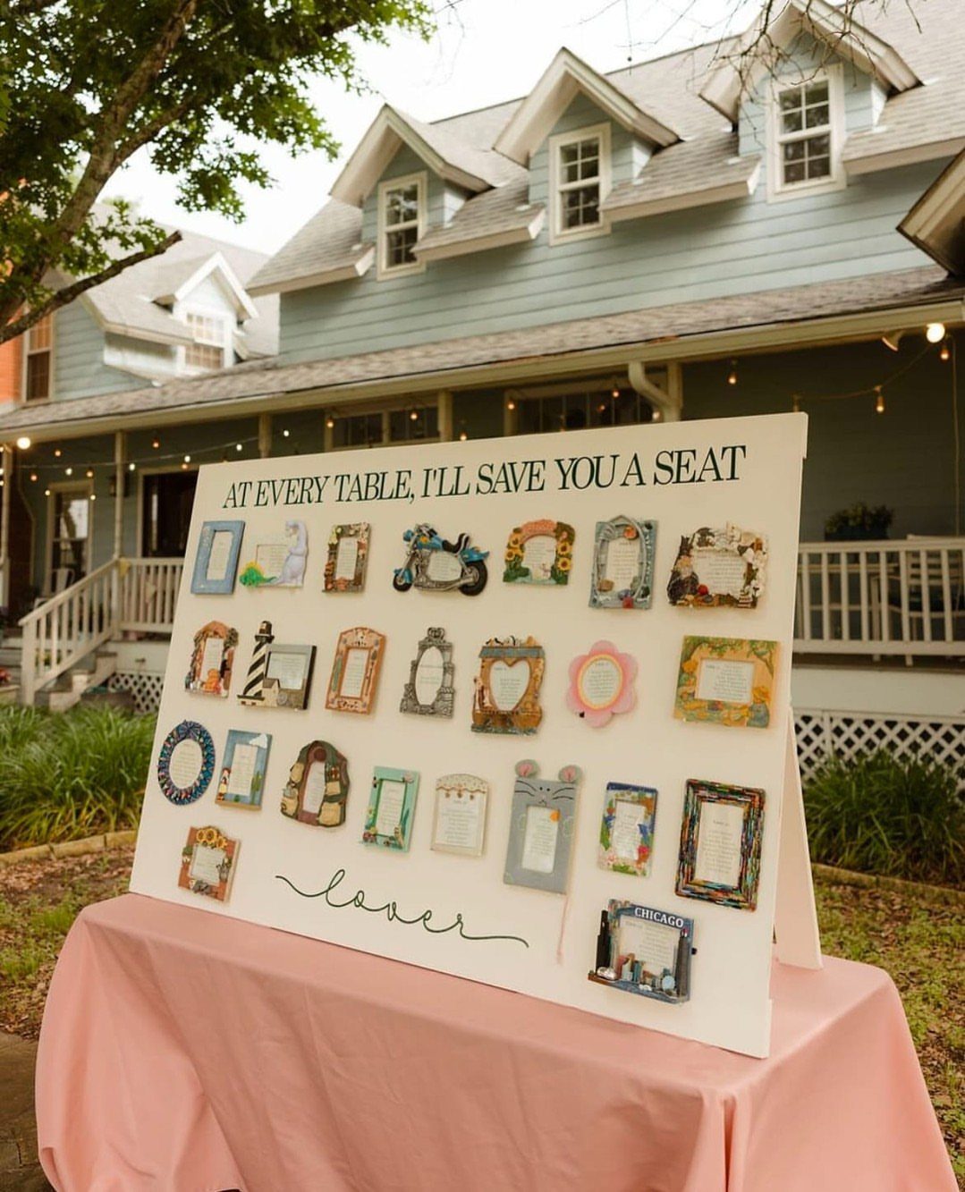 11 Thrifted Wedding Decor Ideas to Steal for Real Budgets 7 A white wedding seating chart sign decorated with many small, colorful, mismatched thrifted picture frames.