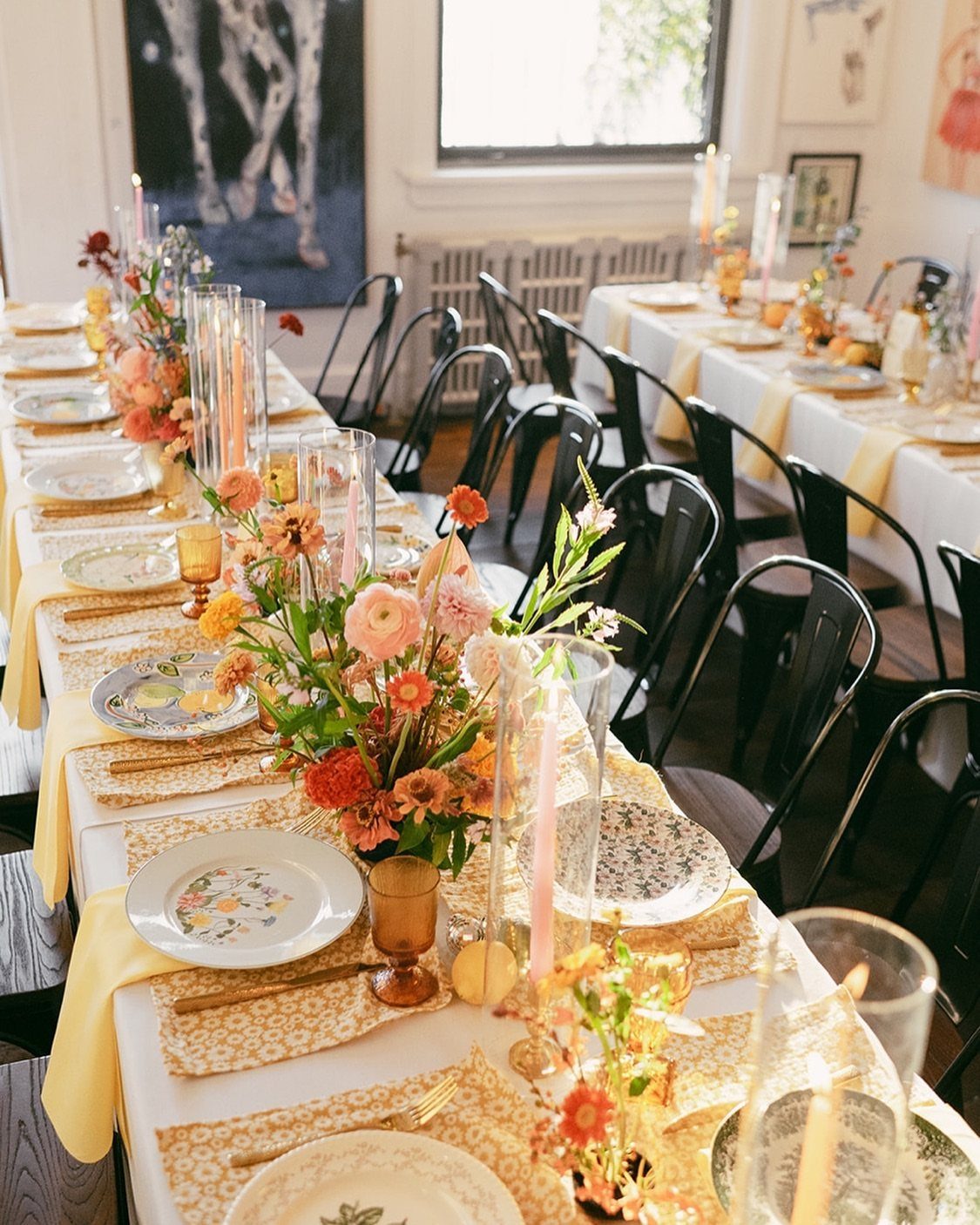 11 Thrifted Wedding Decor Ideas to Steal for Real Budgets 6 A long wedding table decorated with mismatched patterned plates, colorful flowers, and gold cutlery.