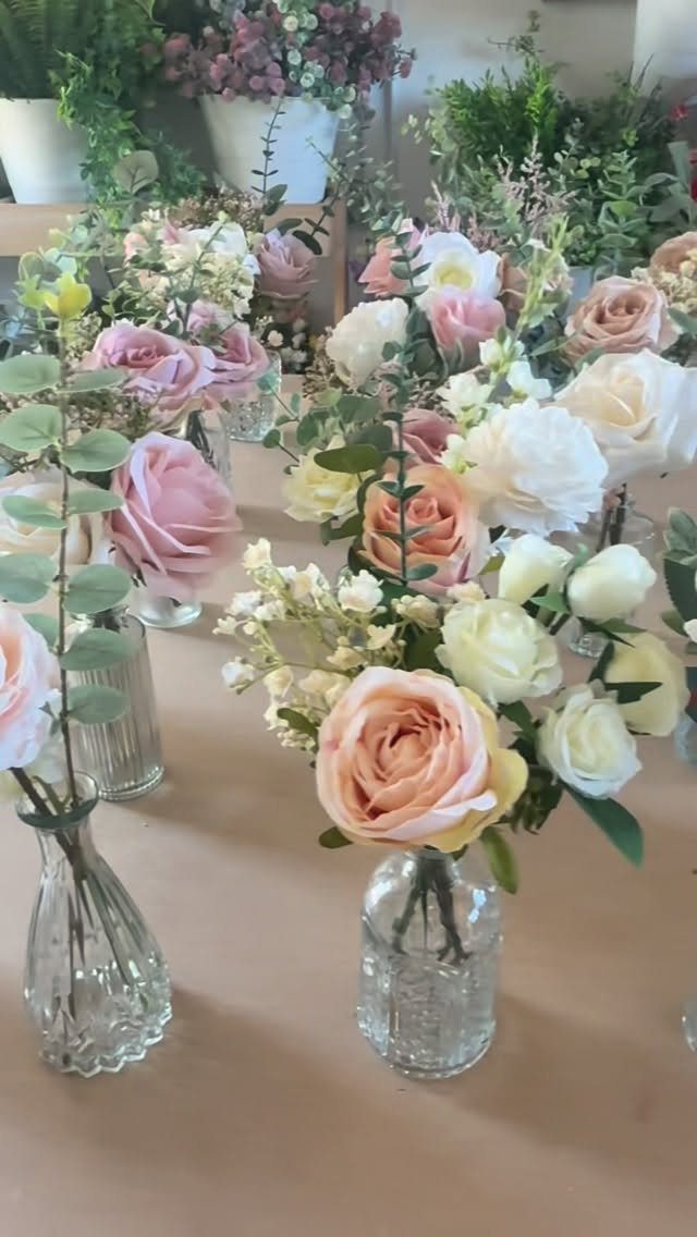 11 Thrifted Wedding Decor Ideas to Steal for Real Budgets 1 Artificial pink and white flowers arranged in small glass vases on a table.