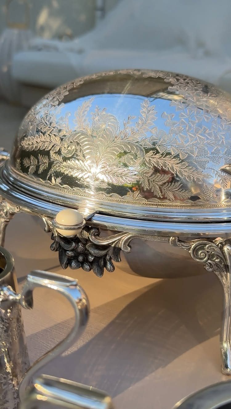 11 Thrifted Wedding Decor Ideas to Steal for Real Budgets 11 Ornate silver serving dish with detailed floral engravings reflecting the bright sky outdoors.