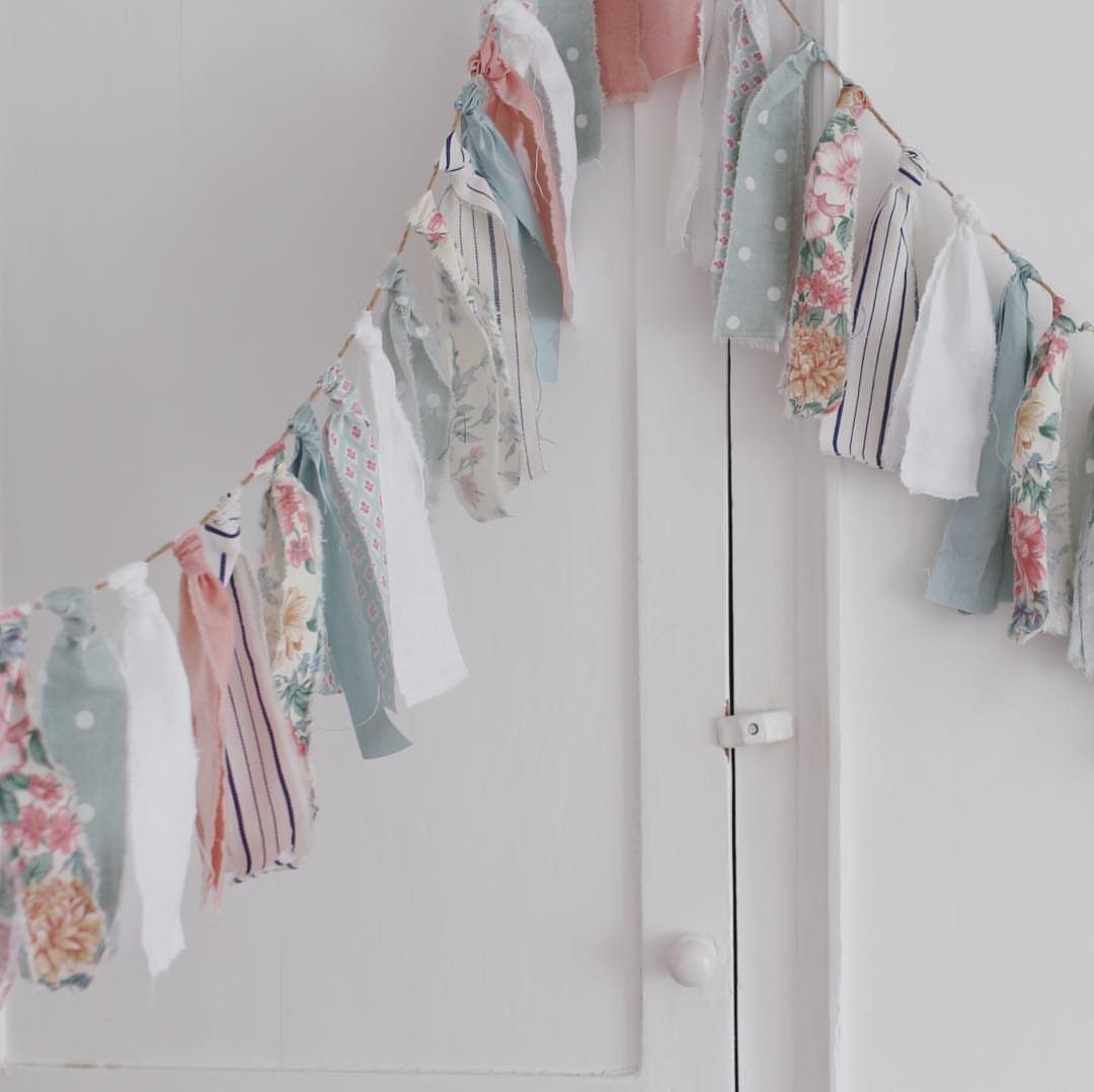Fabric bunting garland with pastel floral and striped patterns hanging against a white wooden door.