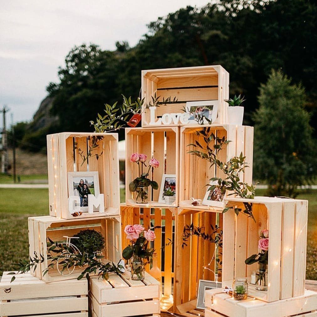 20 Wedding Decor DIY Ideas for Ceremony and Reception 19 Stacked light wooden crates decorated with pink roses, framed photos, and fairy lights outdoors.