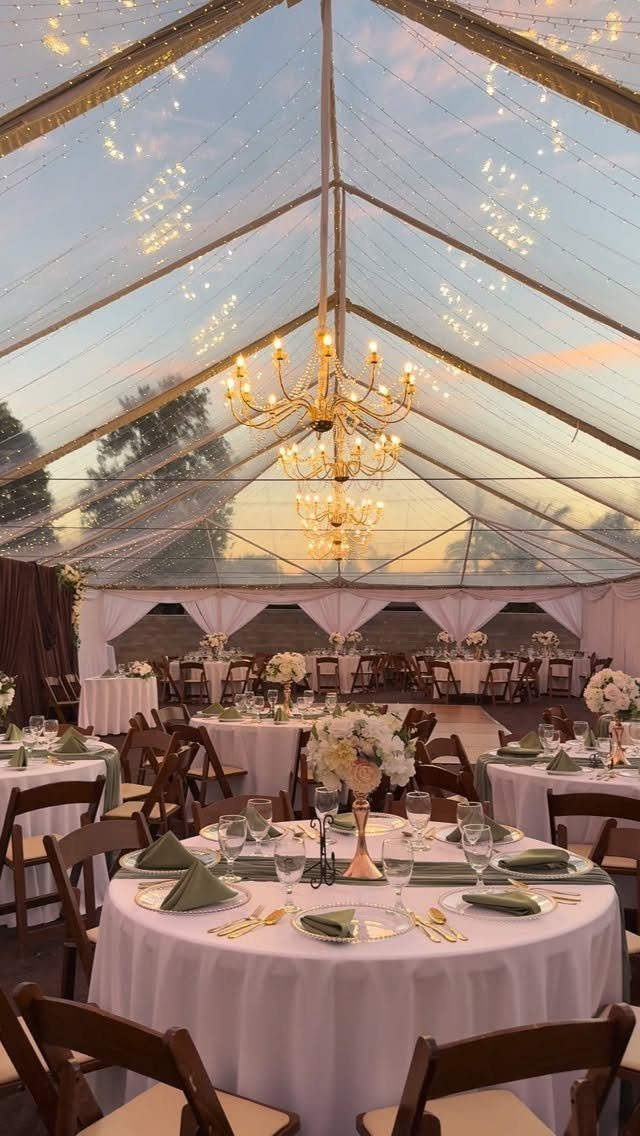 22 Wedding Decor Garden Theme Ideas for Every Reception Style 19 Wedding reception tables set inside a clear marquee tent with chandeliers and twinkle lights at sunset.
