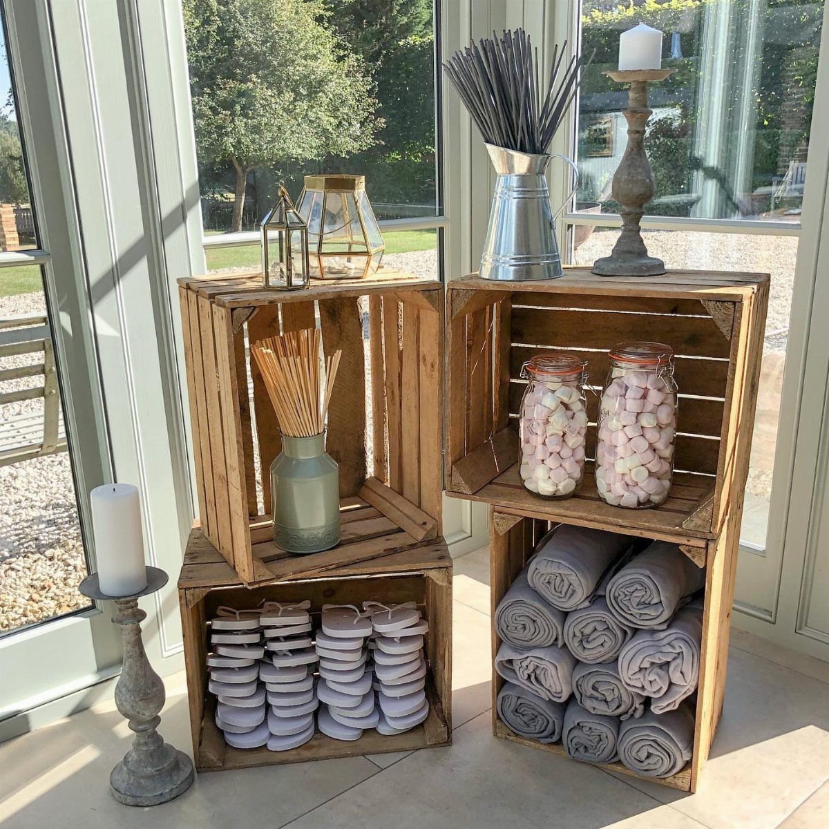 22 Wedding Decor Garden Theme Ideas for Every Reception Style 11 Stacks of grey flip-flops and rolled blankets arranged in wooden crates for wedding guests.