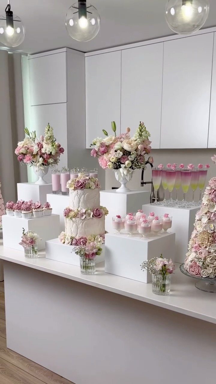 22 Wedding Decor Garden Theme Ideas for Every Reception Style 15 A white tiered wedding cake decorated with pink flowers sits among cupcakes and floral arrangements.