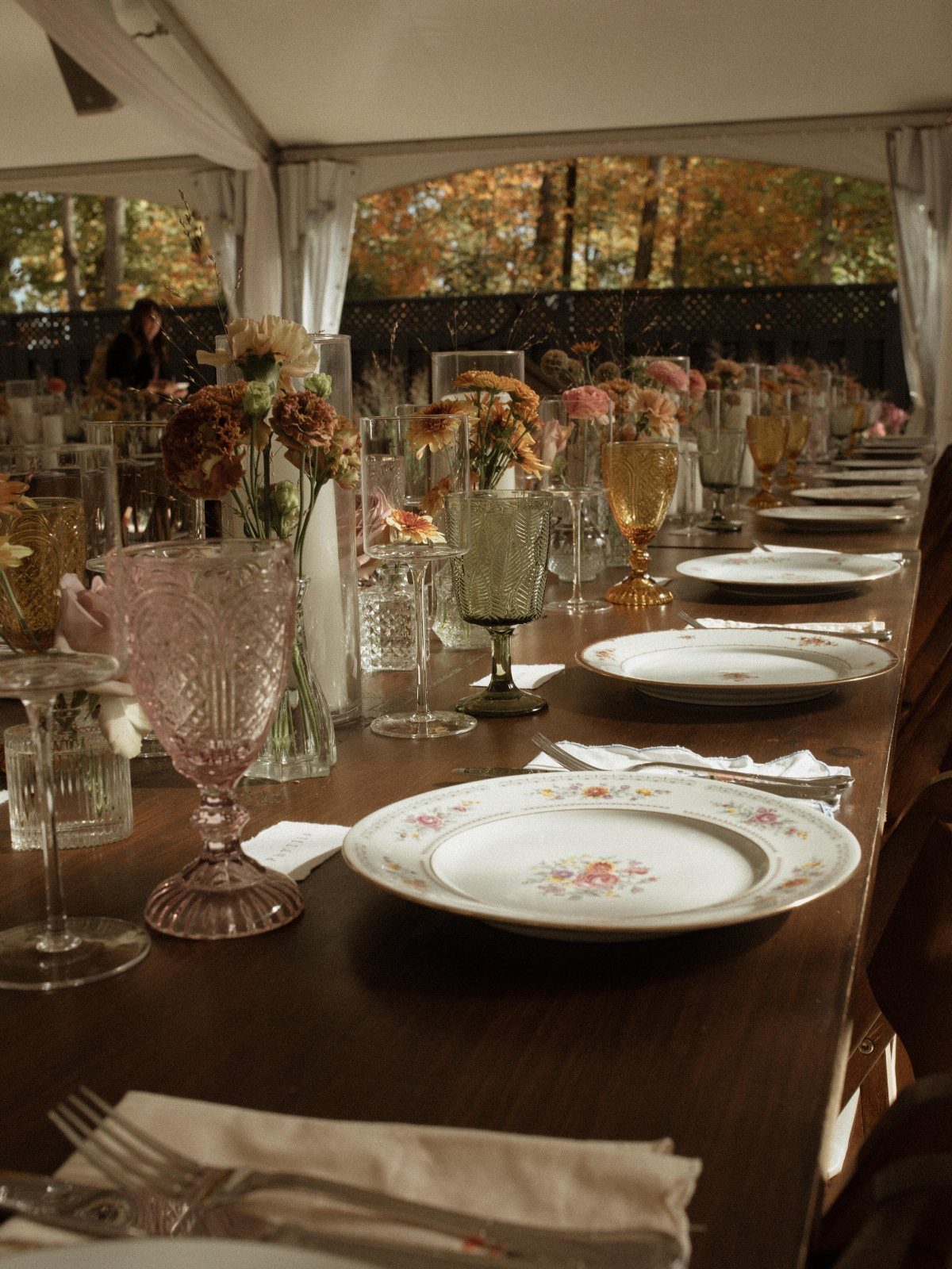 22 Wedding Decor Garden Theme Ideas for Every Reception Style 8 Mismatched vintage glassware and floral patterned plates set on a long wooden dining table.