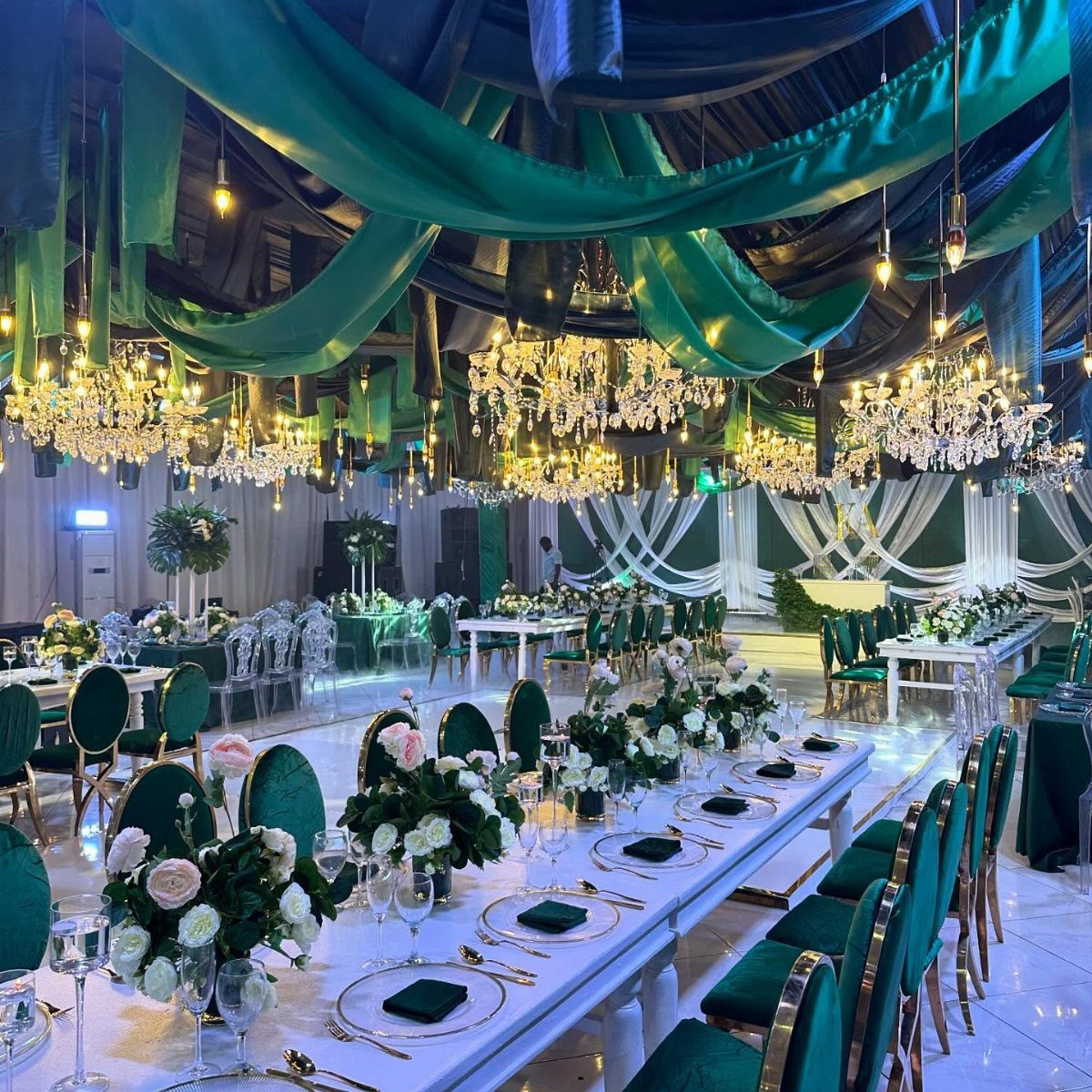11 Wedding Decor Room Ideas for Your Reception in 2026 1 Emerald green and white wedding reception hall with crystal chandeliers and floral table settings.