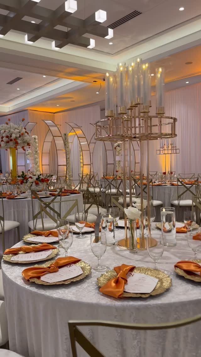 11 Wedding Decor Room Ideas for Your Reception in 2026 7 Wedding reception tables set with gold chargers, orange napkins, and tall gold candelabra centerpieces.