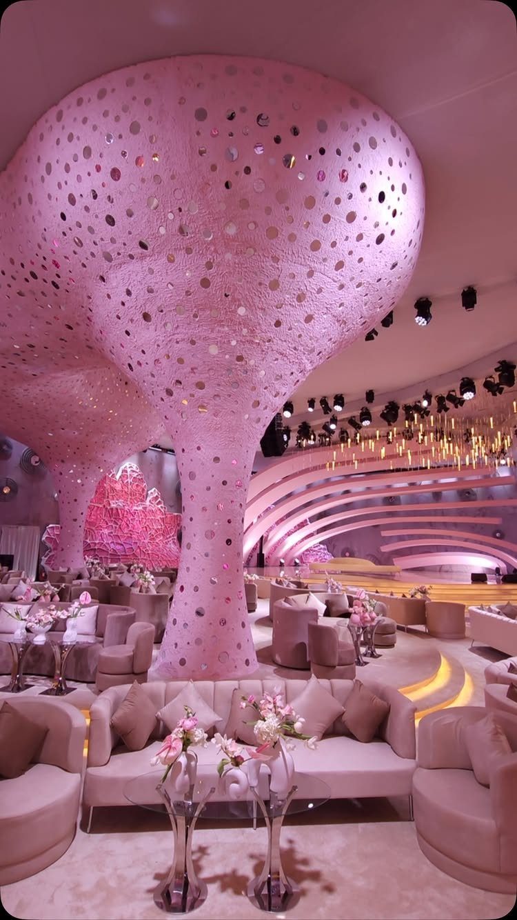 11 Wedding Decor Room Ideas for Your Reception in 2026 4 Pink sculptural pillars stand above plush lounge seating and floral arrangements in a large event space.