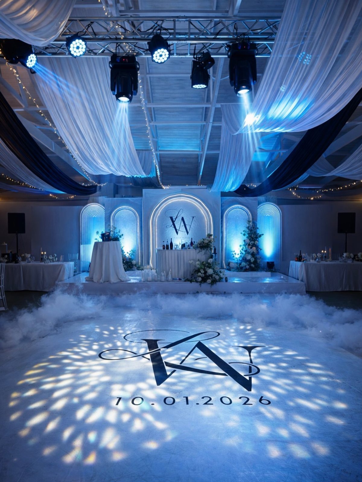 11 Wedding Decor Room Ideas for Your Reception in 2026 11 A wedding reception hall with blue lighting, white fabric draping, and a monogrammed dance floor.