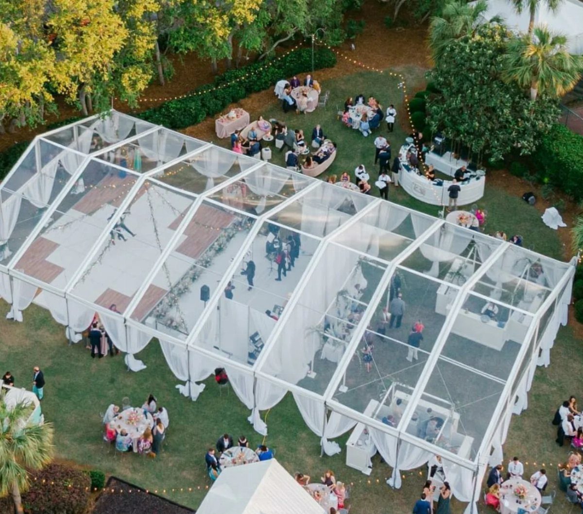 13 Wedding Decor Tent Ideas for 2026 Receptions 4 Aerial view of a large wedding tent featuring a transparent clear top and white fabric draping.